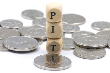 PIT description on the wooden blocks laying on the polish zlotych coins, concept for personal income tax for 2026.