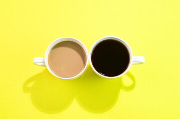 Black coffee and coffee with milk on yellow background.