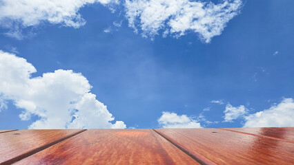 Wooden tabletop with blue sky and clouds. Empty wooden table for product placement.