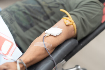 Obraz premium Close-up of a donor’s arm during blood donation on donor chair at blood donation center.Donation for emergency surgery and blood bank unit.Save life and medical treatment concept.