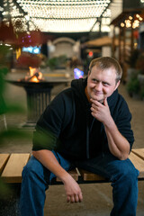 Man in a black hoodie sits thoughtfully