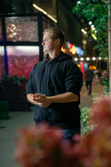 Young man in a black hoodie standing outdoors at night