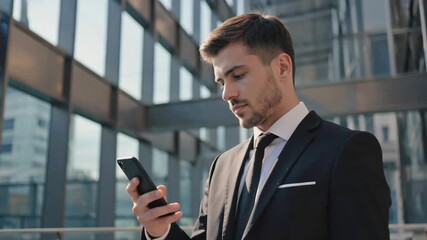 Young caucasian businessman in suit using mobile phone outdoor
