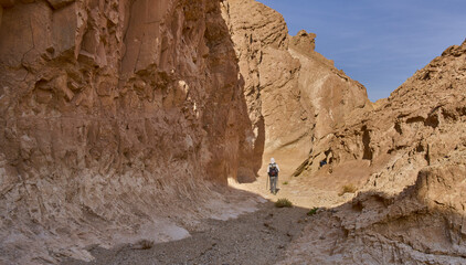 Unique landscape in Eilat Mountains nature reserve, southern Negev, as seen from the Israel Trail pass through the reserve. A male hiker in a trail. Impressive colorful walls of a narrow dry canyon.
