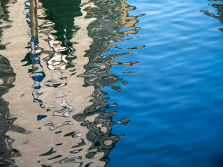 A wooden pole, water, sun, and reflections as abstract artists.