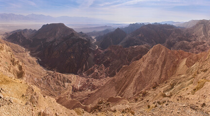 Unique desert landscape of Eilat Mountains reserve. A stark contrast of dark, hard crystalline rock against colorful sandstone and limestone. Copper mineralization. Chain of black volcanic mountains.