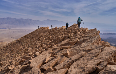 Unique landscape in Eilat Mountains nature reserve, the southern Negev, as seen from the Israel Trail pass through the reserve. A group of hikers passing along a mountain ridge. Active lifestyle.