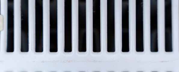 Close-up view of a white ventilation grille with multiple narrow slots for air circulation, ideal for concepts related to home design or air quality systems.