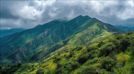 A verdant mountain range stretches skyward beneath a blanket of moody clouds, its slopes adorned with vibrant greenery in a picturesque landscape view.