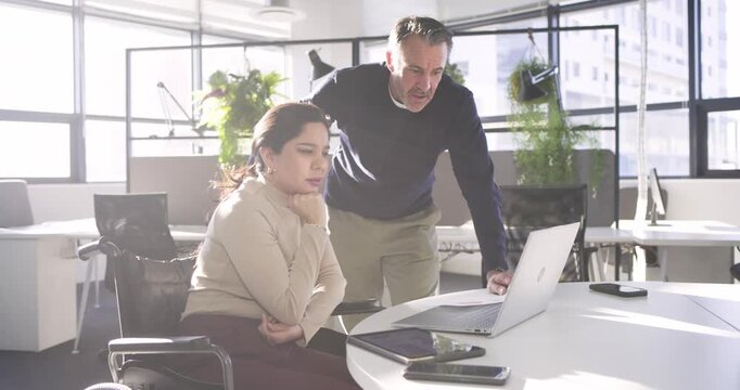 Diverse coworkers triggered by deadline gathering at laptop reviewing charts at office for planning