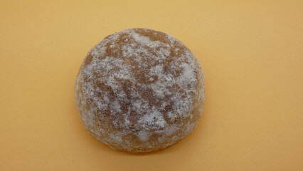 Round rock with a rough surface placed on a yellow background showing texture and natural details near a solid surface