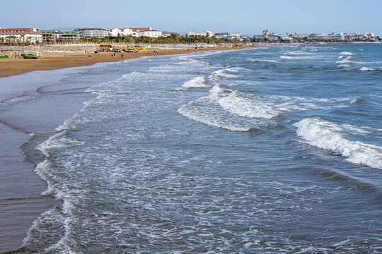 A serene, empty beach with rolling white-capped waves under a spring sun, its infrastructure not yet ready for the high season. A peaceful interlude on the Mediterranean coast. Evrenseki, Antalya, Tur