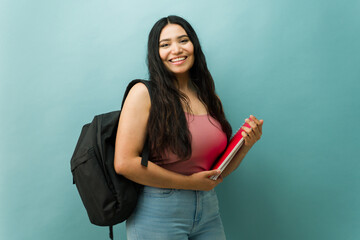 Naklejka premium Latin young woman student posing with backpack and notebooks