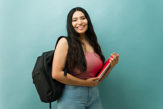 Latin young woman student posing with backpack and notebooks
