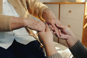 Young hands gently holding older hands, symbolizing care, support, and compassion between generations
