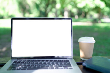 Fototapeta premium Mock up laptop computer, coffee cup on wooden table in the green garden.