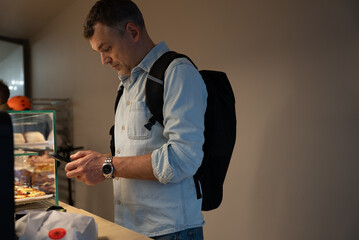 Customer using smartphone to pay at bakery counter with packaged bread on surface