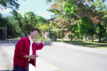 Asian man holding smartphone and meeting friends or call taxi in evening street