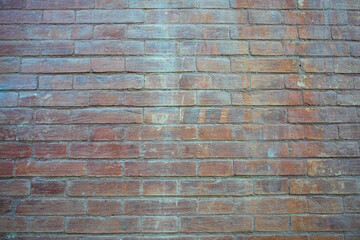 Full view of a large red brick wall with uneven coloration and worn grunge surface