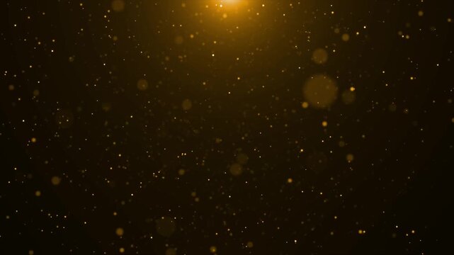 Abstract golden glitter particles falling down from bright light in black space