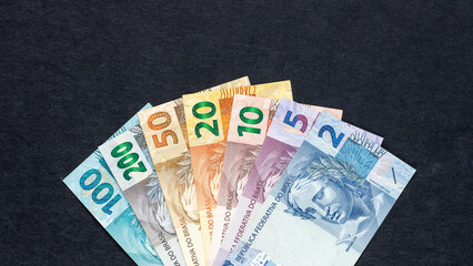 Brazil  money. All Brazilian currency banknotes, reais, arranged in a fan on a black background. Financial business concept. Flat lay. Close up, Copy space