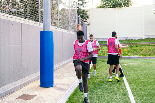 Football players performing warm up exercises on artificial turf. Group of men preparing for a match or practice session - Powered by Adobe