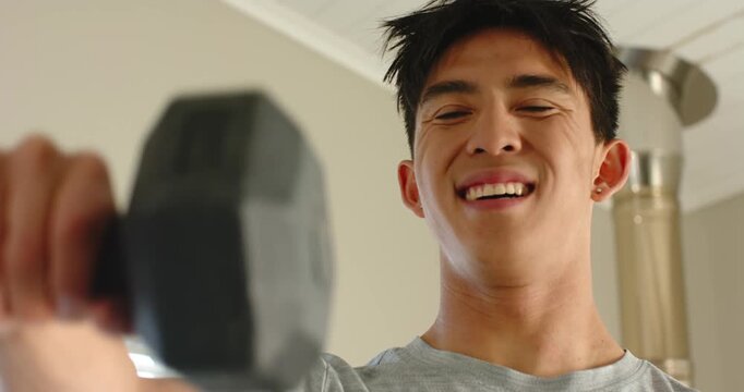 Upon gripping black hex dumbbell near window man is lifting weight to shoulder height for strength