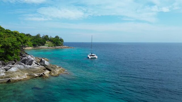 Vacation in Southeast Asia, sea travel in Thailand. A white sailing yacht off the coast of a tropical island, seen from a drone.