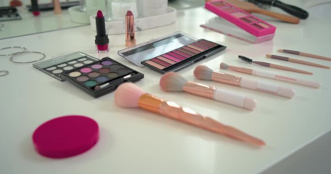 Camera panning right and forward is revealing makeup brushes and palettes to showcase vanity layout