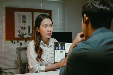 Obraz premium Businesswoman presenting financial data and charts on a tablet to a male colleague, discussing corporate strategy and progress