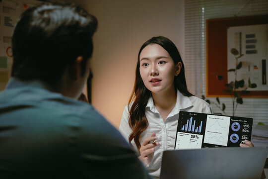Young businesswoman sharing a data analysis report on a digital tablet with a colleague during an important office meeting - Powered by Adobe
