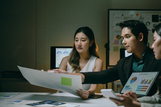 Business team collaborating on financial data and reports in a modern office setup, analyzing charts on screens and documents