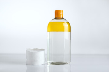 Minimalist scene featuring a two-phase makeup remover with oil and cotton pads