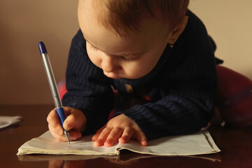 A focused toddler making first attempts at writing.