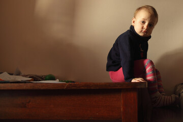 A quiet emotional moment in warm afternoon light. A child pausing in silence, lost in her own thoughts. Copy space for text or design.