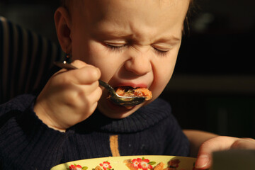A child expressing strong emotions during early self-feeding attempts.