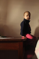 A toddler sitting quietly on a table, bathed in warm natural light. Copy space for design.