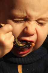 A toddler learning to eat independently, showing a funny concentrated face.