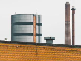Industrial buildings located in Boras, Sweden, showing a water tower and smokestack against a cloudy sky on a cool day
