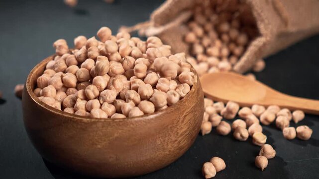 Сhickpeas fall into a wooden bowl. slow motion.