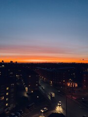 Vibrant Sunset Over the City Streets; stunning sunset illuminates the city skyline with vivid orange and red hues fading into deep blue