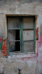 Window, glass panes with chipped green frames, in cement and brick wall 