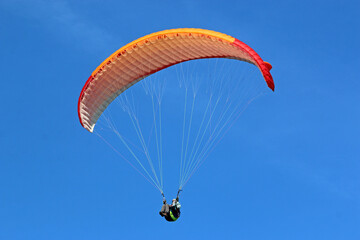 Paraglider flying in a blue sky	