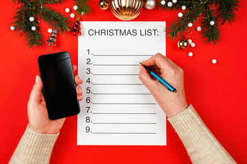 Christmas plans list. Woman's hands holding a smartphone and writing down a list of Christmas...