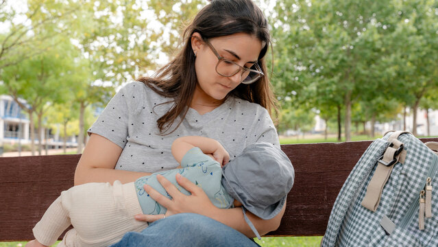 Mother caring for baby while sitting on a park bench