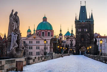 Fototapeten Prag The UNESCO world heritage site Charles Bridge covered in snow with shining lamps in Prague in the winter morning dawn.   © Ondrej Bucek