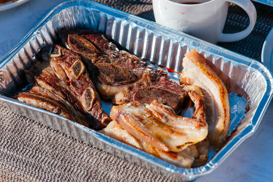 Deliciously grilled ribs in a shiny aluminum tray