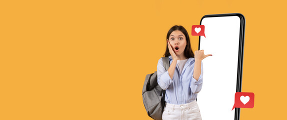 A young woman stands in front of a large smartphone with a cheerful expression. She appears surprised and delighted, showcasing social media engagement. The bright background enhances her excitement.
