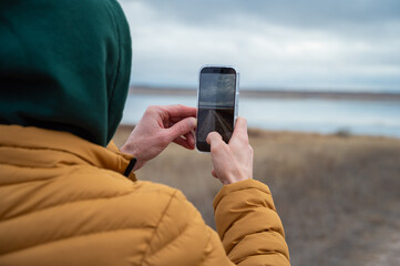 a man in a mustard-colored jacket takes a photo on a mobile phone