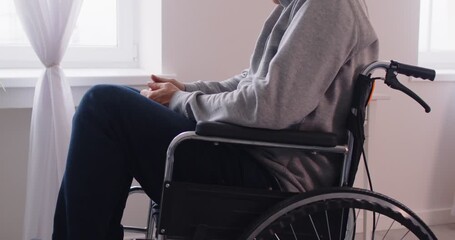 Close up cropped view of upset man sitting alone in wheelchair during rehabilitation after injury or stroke. Disabled lonely person feeling emotional distress or frustration, reflecting on challenges. - Powered by Adobe